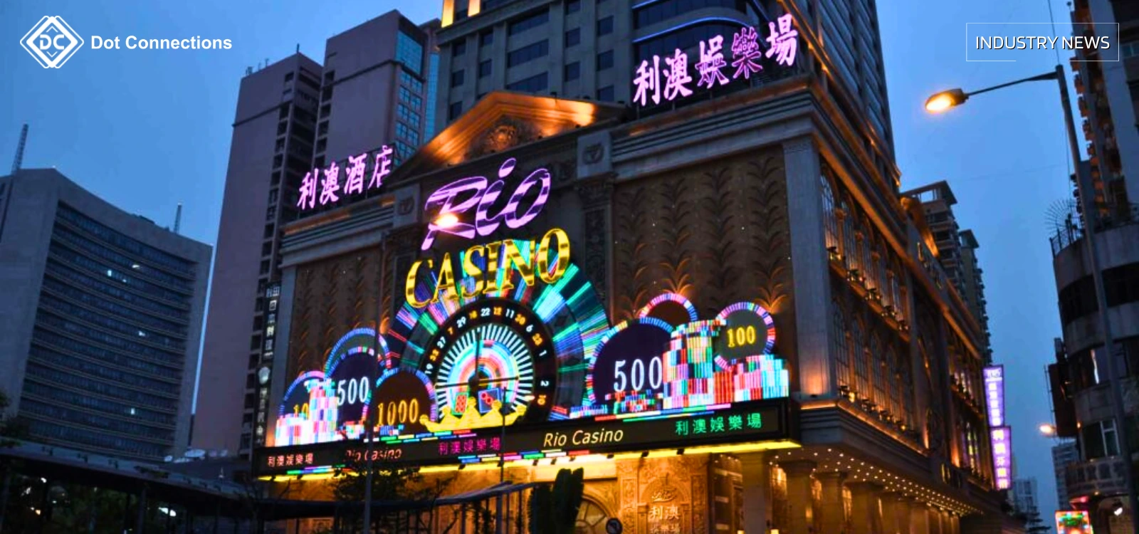 Rio Casino facade lit by neon signs on a Macau street at dusk